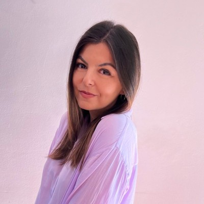 Portrait of a woman with brown hair on a flat gray background.